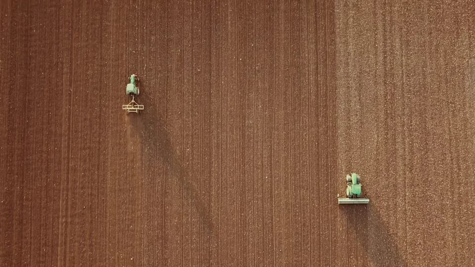 An aerial view of farm machinery working a field in animal.